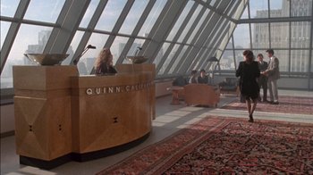 Movie still from “Class Action” (1991), directed by Michael Apted – A woman sitting at a desk in front of a large window; Wide shot, High angle
