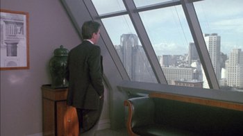 Movie still from “Class Action” (1991), directed by Michael Apted – A man standing in front of a window looking at a city skyline; Wide shot, High angle