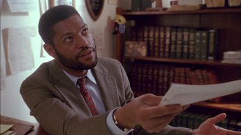 Movie still from “Class Action” (1991), directed by Michael Apted – A man in a suit and tie holding a cell phone in his hand; Close Up shot, Over the shoulder angle