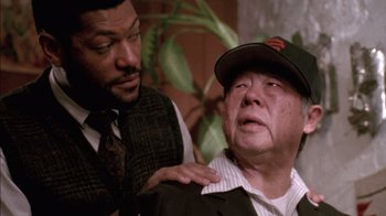Movie still from “Class Action” (1991), directed by Michael Apted – A man in a baseball cap is being hugged by another man in a suit; Close Up shot, Over the shoulder angle