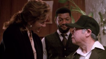 Movie still from “Class Action” (1991), directed by Michael Apted – A group of people that are standing around talking to each other; Medium shot, Over the shoulder angle