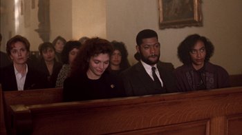 Movie still from “Class Action” (1991), directed by Michael Apted – A group of people sitting in front of a wooden wall; Medium shot, High angle