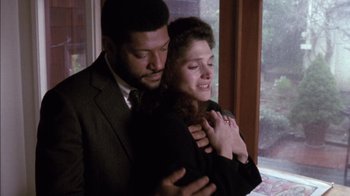 Movie still from “Class Action” (1991), directed by Michael Apted – A man and a woman hugging in front of a window; Medium shot, High angle