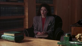 Movie still from “Class Action” (1991), directed by Michael Apted – A woman sitting in a chair in front of a table; Medium shot, High angle