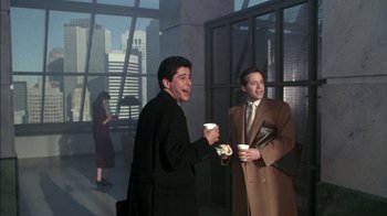 Movie still from “Class Action” (1991), directed by Michael Apted – Two men in suits are holding coffee cups and smiling; Medium shot, Over the shoulder angle