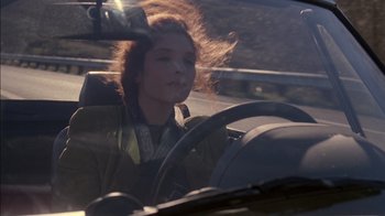 Movie still from “Class Action” (1991), directed by Michael Apted – A woman sitting in the driver's seat of a car; Close Up shot, Low angle