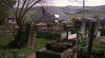 Movie still from “Class Action” (1991), directed by Michael Apted – An old man standing in a garden with a bunch of pots on the ground; Wide shot, High angle