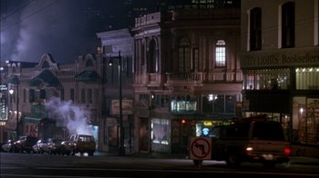 Movie still from “Class Action” (1991), directed by Michael Apted – A car driving down a street next to tall buildings at night; Extreme Wide shot, High angle