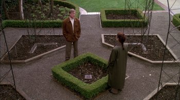 Movie still from “Class Action” (1991), directed by Michael Apted – A man and a woman standing in the middle of a garden; Wide shot, High angle