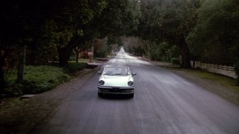 Movie still from “Class Action” (1991), directed by Michael Apted – A car driving down a street near trees; Extreme Wide shot, High angle