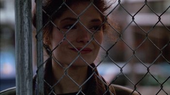 Movie still from “Class Action” (1991), directed by Michael Apted – A woman looking through a chain link fence at night; Close Up shot, Over the shoulder angle