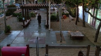 Movie still from “Class Action” (1991), directed by Michael Apted – A man walking down a sidewalk near a park; Extreme Wide shot, High angle