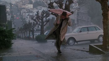 Movie still from “Class Action” (1991), directed by Michael Apted – A man walking down the street holding an umbrella; Wide shot, High angle