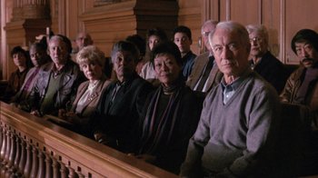 Movie still from “Class Action” (1991), directed by Michael Apted – A group of people sitting in front of a wooden bench; Medium shot, High angle