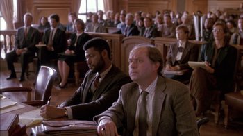 Movie still from “Class Action” (1991), directed by Michael Apted – Two men in suits and ties sitting in front of an audience; Medium shot, High angle