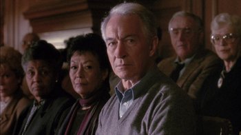 Movie still from “Class Action” (1991), directed by Michael Apted – An older man and woman standing next to each other in front of other people; Close Up shot, High angle