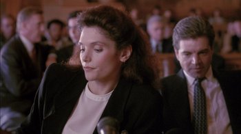 Movie still from “Class Action” (1991), directed by Michael Apted – A woman in a crowd of people sitting in a room; Close Up shot, Over the shoulder angle
