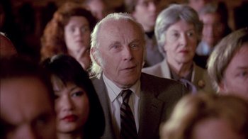 Movie still from “Class Action” (1991), directed by Michael Apted – An older man in a suit and tie in front of a group of older people; Close Up shot, Over the shoulder angle