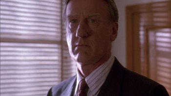 Movie still from “Class Action” (1991), directed by Michael Apted – A man in a suit and tie in front of a window; Close Up shot, Low angle