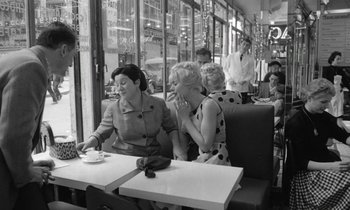 Movie still from “Cléo from 5 to 7” (1962), directed by Agnès Varda – A group of women sitting at a table in front of a window; Medium shot, High angle