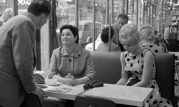 Movie still from “Cléo from 5 to 7” (1962), directed by Agnès Varda – A group of people sitting at a table in front of a window; Medium shot, Over the shoulder angle
