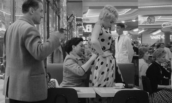 Movie still from “Cléo from 5 to 7” (1962), directed by Agnès Varda – A woman in a polka dot dress is helping another woman with her dress; Medium shot, Over the shoulder angle