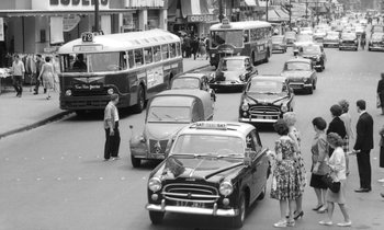 Movie still from “Cléo from 5 to 7” (1962), directed by Agnès Varda – An old black and white photo of a busy city street; Extreme Wide shot, High angle