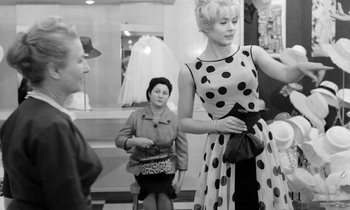 Movie still from “Cléo from 5 to 7” (1962), directed by Agnès Varda – A woman in a polka dot dress holding a purse; Medium shot, Over the shoulder angle