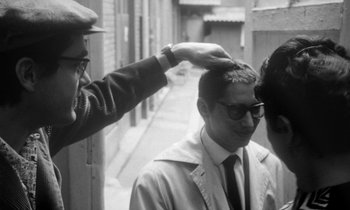 Movie still from “Cléo from 5 to 7” (1962), directed by Agnès Varda – An old photo of a man getting his head shaved; Close Up shot, Over the shoulder angle