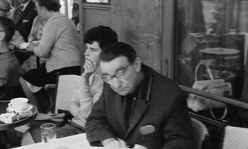 Movie still from “Cléo from 5 to 7” (1962), directed by Agnès Varda – An older man sitting at a table in front of a woman; Medium shot, Over the shoulder angle