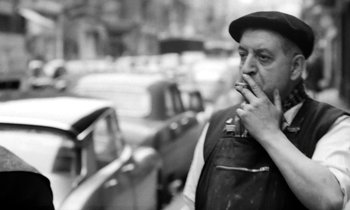 Movie still from “Cléo from 5 to 7” (1962), directed by Agnès Varda – A man smoking a cigarette while standing next to parked cars; Close Up shot, Low angle