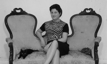 Movie still from “Cléo from 5 to 7” (1962), directed by Agnès Varda – A black and white photo of a woman sitting on a couch with a cat; Medium shot, High angle