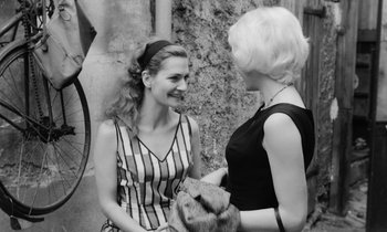 Movie still from “Cléo from 5 to 7” (1962), directed by Agnès Varda – Two young women are talking to each other outside; Medium shot, Over the shoulder angle