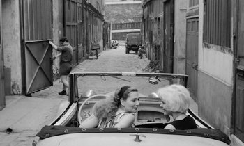 Movie still from “Cléo from 5 to 7” (1962), directed by Agnès Varda – Two women in the back seat of a convertible car; Wide shot, High angle