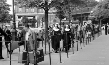 Movie still from “Cléo from 5 to 7” (1962), directed by Agnès Varda – A black and white photo of a group of people walking down a street; Wide shot, High angle