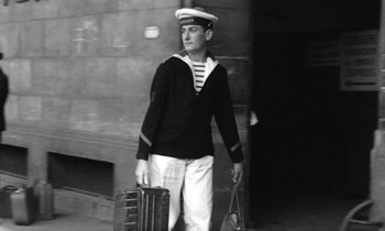 Movie still from “Cléo from 5 to 7” (1962), directed by Agnès Varda – A man in a sailor's uniform carrying a suit case; Medium shot, Low angle