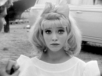 Movie still from “Cléo from 5 to 7” (1962), directed by Agnès Varda – A black and white photo of a woman with a bow in her hair; Close Up shot, High angle