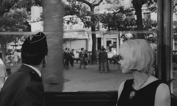 Movie still from “Cléo from 5 to 7” (1962), directed by Agnès Varda – A black - and - white photo of people walking on a street; Medium shot, Over the shoulder angle