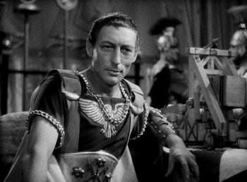 Movie still from “Cleopatra” (1934), directed by Cecil B. DeMille – A man in a roman outfit is posing for a picture; Medium shot, Low angle