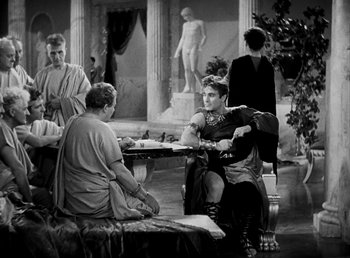 Movie still from “Cleopatra” (1934), directed by Cecil B. DeMille – A group of people sitting around a table; Wide shot, Over the shoulder angle