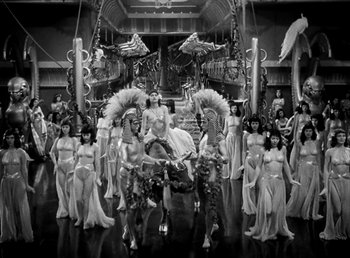 Movie still from “Cleopatra” (1934), directed by Cecil B. DeMille – A black and white photo of a woman on a horse surrounded by women; Wide shot, High angle