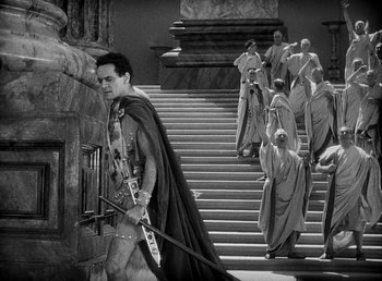 Movie still from “Cleopatra” (1934), directed by Cecil B. DeMille – A man dressed as a roman soldier walking down the steps of a building; Wide shot, High angle
