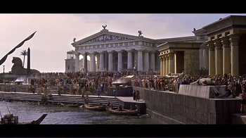 Movie still from “Cleopatra” (1963), directed by Rouben Mamoulian – A crowd of people standing on a pier near a body of water; Extreme Wide shot, High angle
