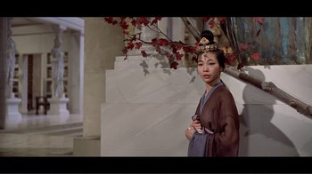 Movie still from “Cleopatra” (1963), directed by Rouben Mamoulian – A woman in a traditional chinese dress standing in front of a tree; Medium shot, Low angle