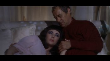 Movie still from “Cleopatra” (1963), directed by Rouben Mamoulian – A man and a woman sitting next to each other on a couch; Medium shot, High angle