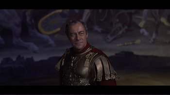 Movie still from “Cleopatra” (1963), directed by Rouben Mamoulian – A man in a roman soldier outfit standing in front of a painting; Close Up shot, Over the shoulder angle