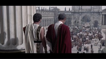 Movie still from “Cleopatra” (1963), directed by Rouben Mamoulian – Two men in roman garb walking in front of a crowd of onlookers; Wide shot, High angle