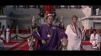 Movie still from “Cleopatra” (1963), directed by Rouben Mamoulian – A man sitting on a throne in front of a crowd; Medium shot, Low angle