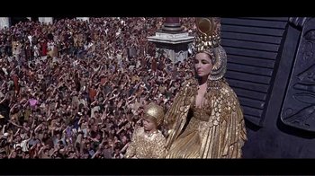 Movie still from “Cleopatra” (1963), directed by Rouben Mamoulian – A crowd of people watching a woman in a gold costume; Wide shot, High angle