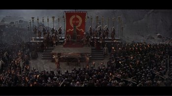 Movie still from “Cleopatra” (1963), directed by Rouben Mamoulian – A crowd of people standing in front of a red flag; Extreme Wide shot, High angle
